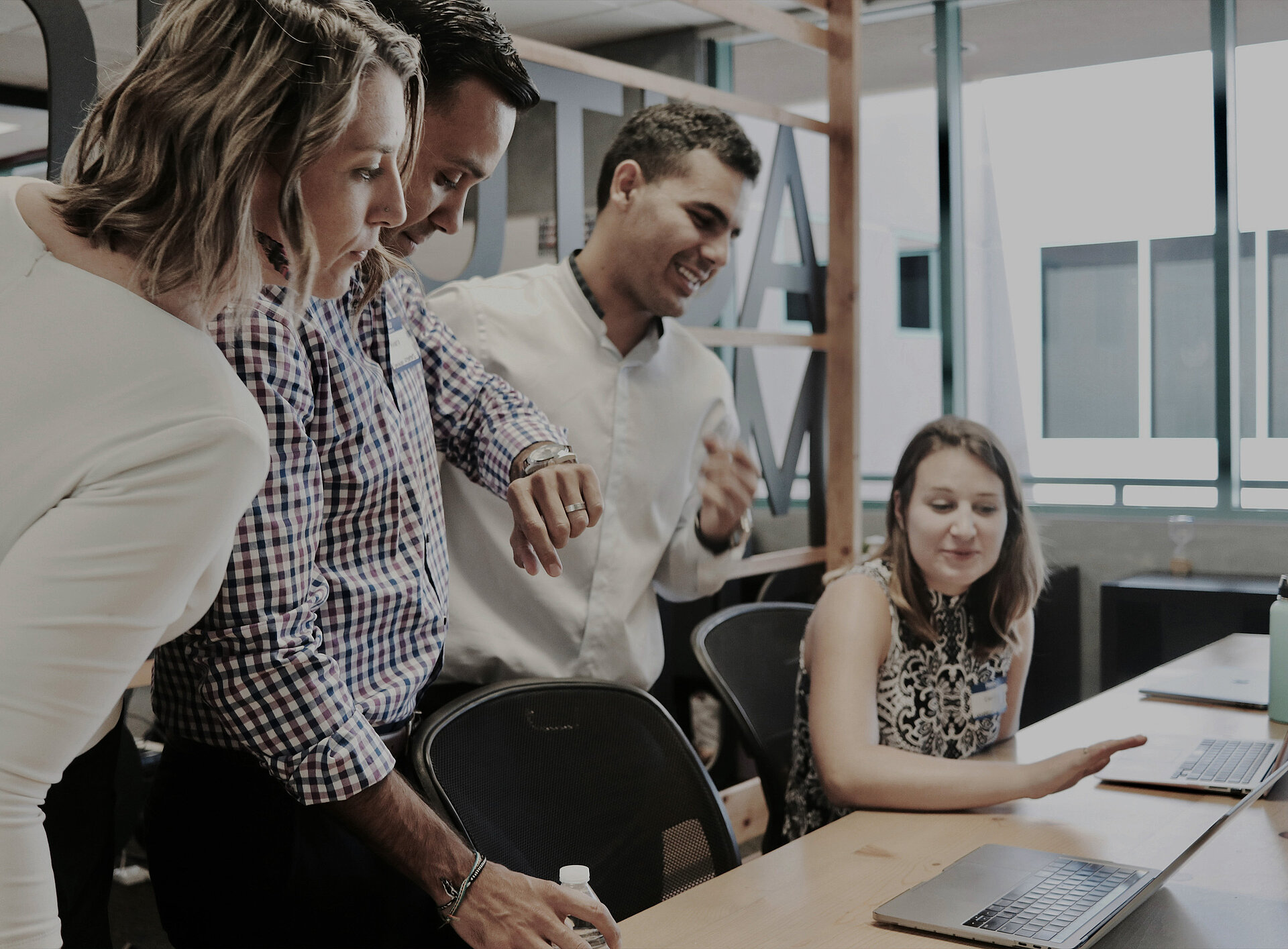 Vier Personen führen eine Unterhaltung, eine Person zeigt etwas am Laptop