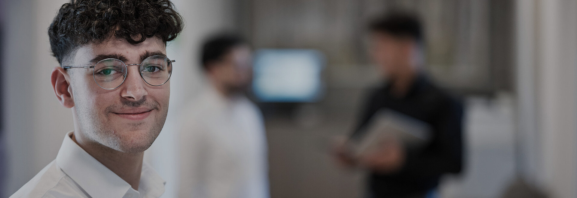 Ein junger Steuerberater lächelt in die Kamera.