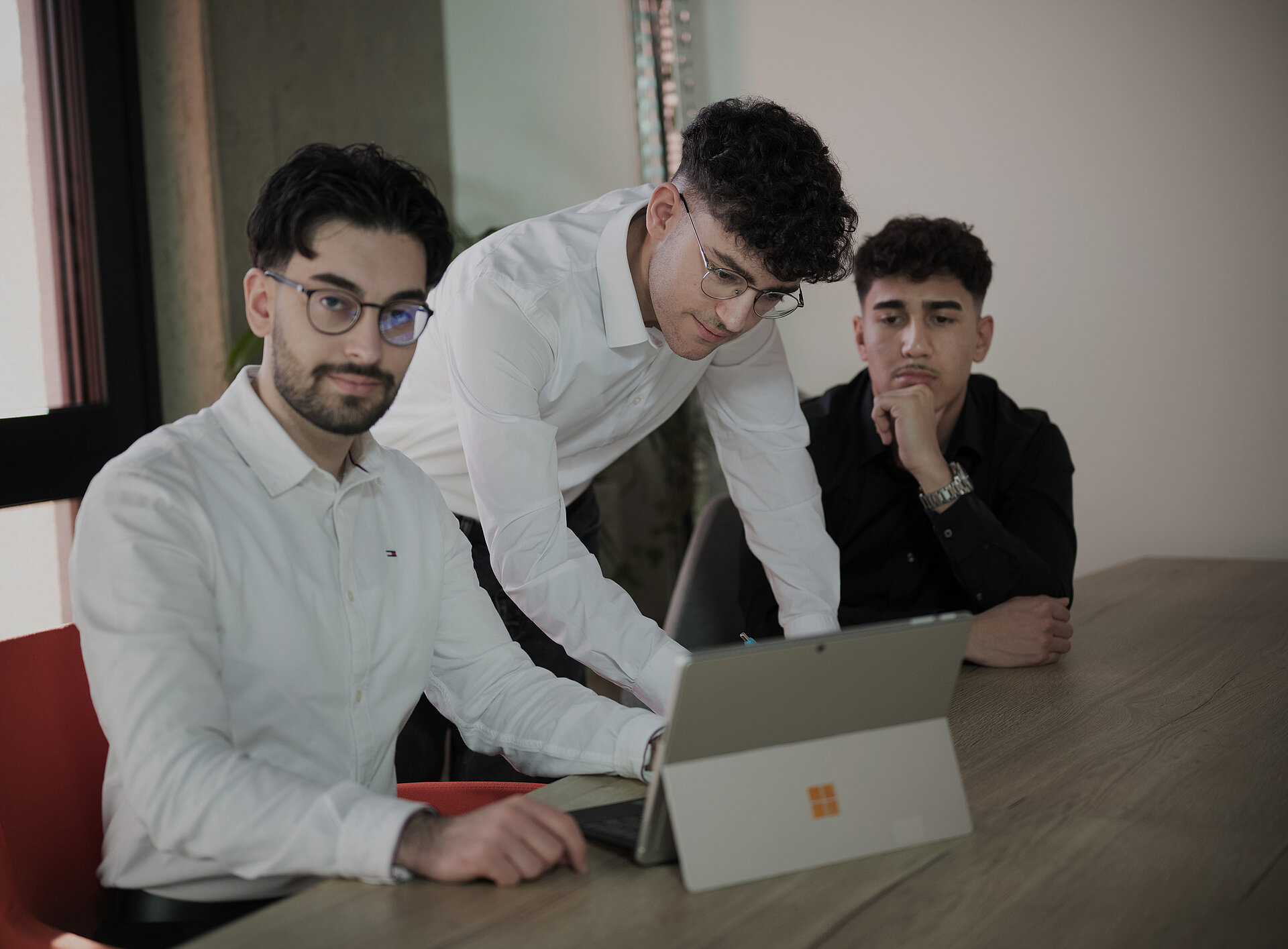 Drei Mitarbeiter sitzen vor einem Laptop und unterhalten sich.