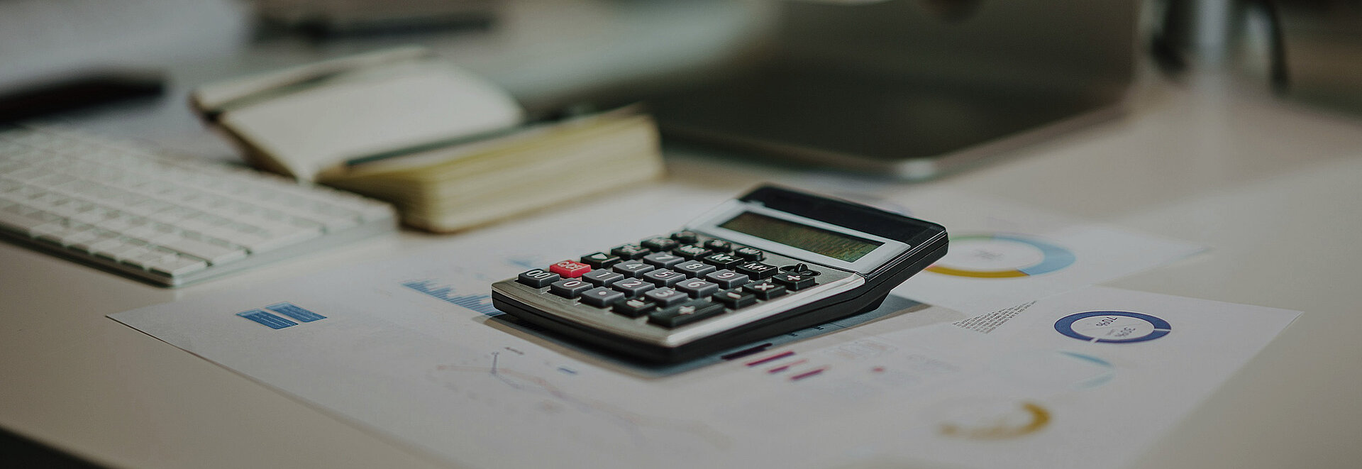 Ein Schreibtisch mit Arbeitsmaterial, in der Mitte liegt ein Taschenrechner